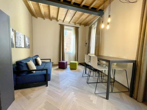 a living room with a blue couch and a table at Appartamenti Saragozza a due passi da Piazza Grande - WIFI e parcheggio gratuito in Modena