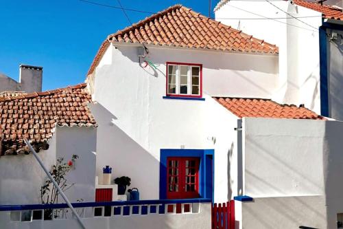a white house with red door and red window at Boutique Surf House in Surf Paradise in Santo Isidoro