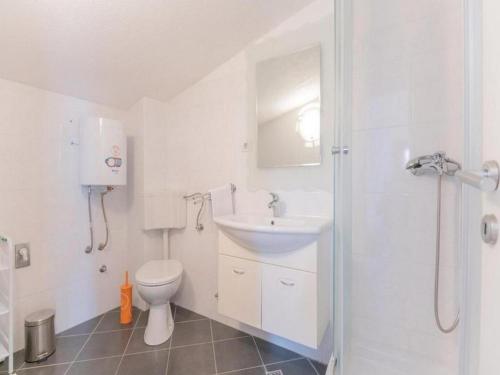 a white bathroom with a sink and a toilet at Relaxing Villa with swimming pool, jacuzzi and entertainment equipment in Podgora