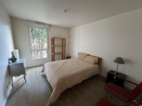 une chambre avec un lit, une fenêtre et une chaise dans l'établissement Appartement aux portes de Paris, à Saint-Ouen