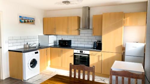 a kitchen with wooden cabinets and a washer and dryer at Sidemersey Livings - Central and Quiet 2-Bedroom Apartment in Liverpool