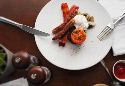 a plate of food with bacon and eggs on a table at The White Horse Inn in Pulborough
