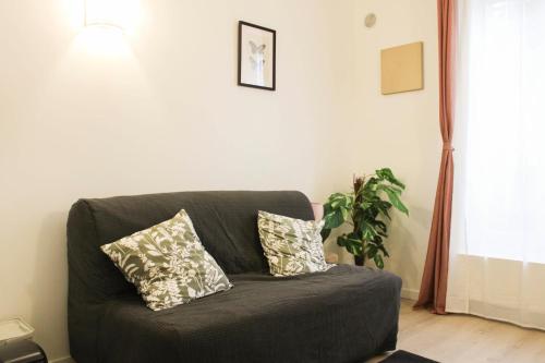 - un canapé avec deux oreillers dans le salon dans l'établissement Charming studio for two at the gates of Paris, à Aubervilliers