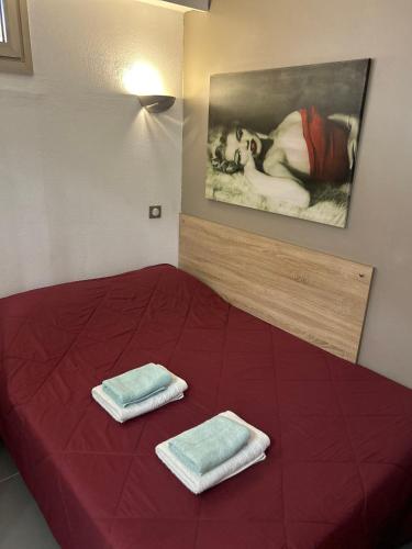- un lit rouge avec 2 serviettes dans l'établissement GOLFE JUAN Joli F2 clim piscine à 5 minutes de la mer, à Vallauris