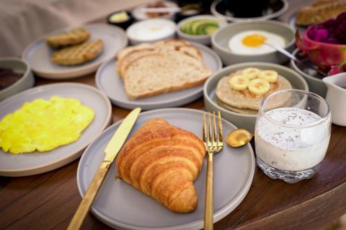 a table with plates of breakfast foods and eggs and bread at Inlander Villas A- Private pool luxury Villa in Gili Trawangan
