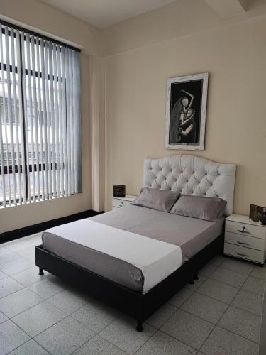 a bedroom with a large bed and a large window at La gran mansión en el centro de Pereira in Pereira