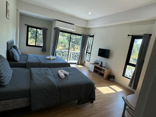 1 Schlafzimmer mit 2 Betten, einem TV und Fenstern in der Unterkunft เดอะซันทูมูนโฮสเทล in Ban Hua Wiang Nua