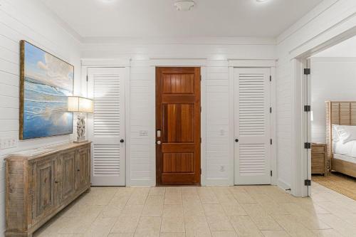 a hallway with white walls and a wooden door at Hope Town Pearl Cottage in Rosemary Beach