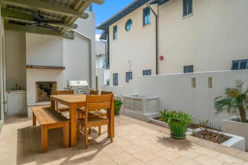a patio with a wooden table and chairs and a house at Hope Town Pearl Cottage in Rosemary Beach