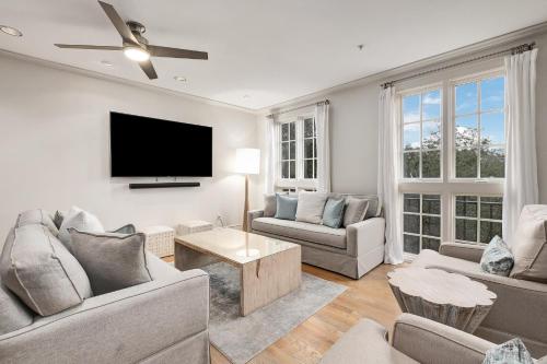 a living room with two couches and a flat screen tv at Rose at Mercado in Rosemary Beach