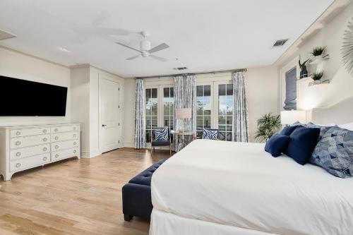 a bedroom with a large bed and a flat screen tv at Rose at Mercado in Rosemary Beach