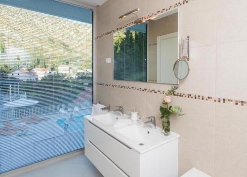 a bathroom with a sink and a mirror and a window at Exclusive Villa with Sea View in Zaton