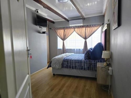 un dormitorio con una cama y una ventana en Botshe Lodge in Vanderbiljpark, en Vanderbijlpark