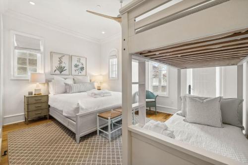 a white bedroom with a bed and a desk at Water Cottage and Carriage House in Rosemary Beach