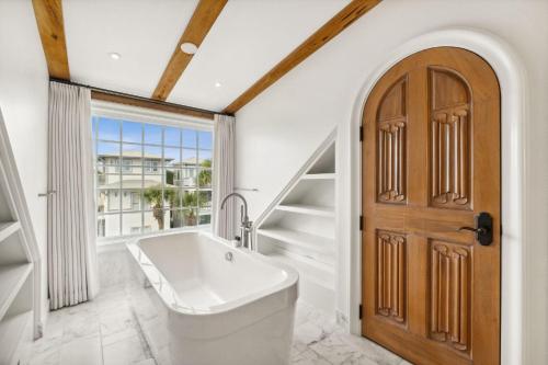 a bathroom with a tub and a wooden door at Water Cottage and Carriage House in Rosemary Beach