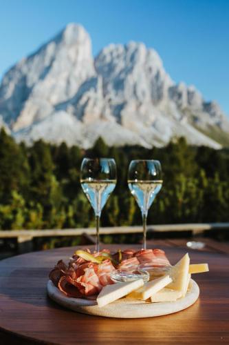 a plate of food and two wine glasses on a table at Ütia De Börz in San Martino in Badia