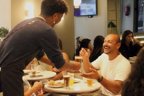 Un hombre le entrega una comida a otro hombre en un restaurante. en Gspot Hostels & Love Triangles Pizzeria, en Lisboa
