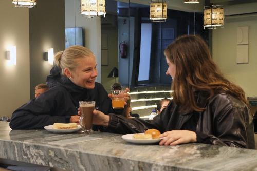 Dos mujeres sentadas en una mesa con platos de comida. en Gspot Hostels & Love Triangles Pizzeria, en Lisboa