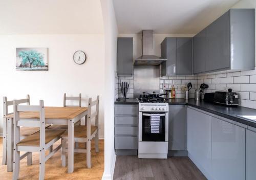a kitchen with a table and a stove top oven at Stylish Crawley 1BR with Private Garden Free Parking Near Gatwick LGW in Three Bridges
