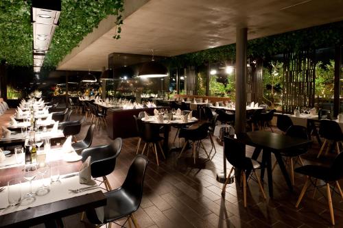 een restaurant met witte tafels, stoelen en planten bij Philippos Xenia Hotel in Serres