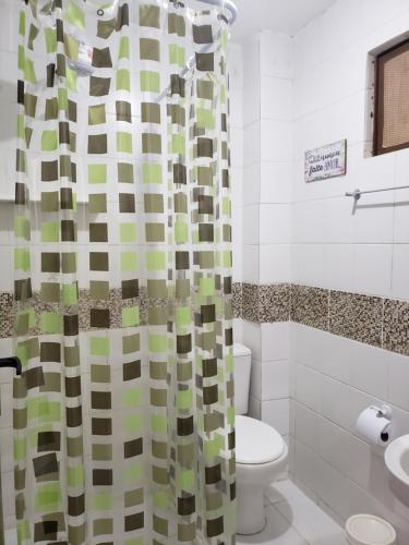 a bathroom with a toilet and a shower curtain at Pousada Recanto da Enseada in Cabo de Santo Agostinho