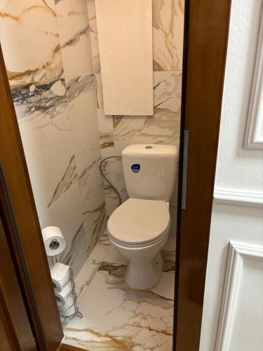 a bathroom with a toilet and marble walls at City Heart Luxury Apartment in Nové Zámky