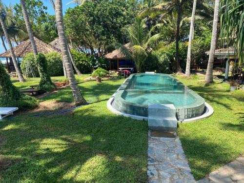 ウナワトゥナにあるRockside Cabanas Hotelのヤシの木が茂る庭のスイミングプール