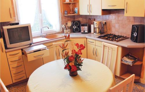 une cuisine avec une table et un vase avec des fleurs. dans l'établissement 3 Bedroom Lovely Home In Landudec, à Landudec