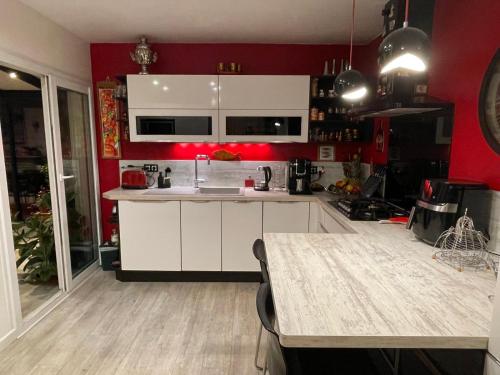 eine Küche mit weißen Schränken und roten Wänden in der Unterkunft Charmante maison pour vos vacances in La Rochelle