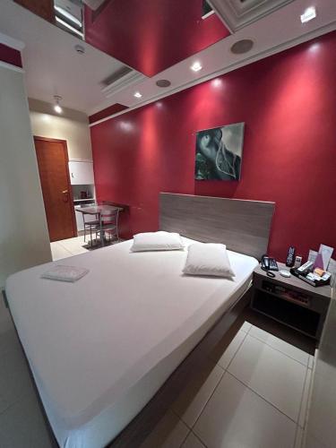 a large white bed in a room with a red wall at Alpha Motel in Amparo