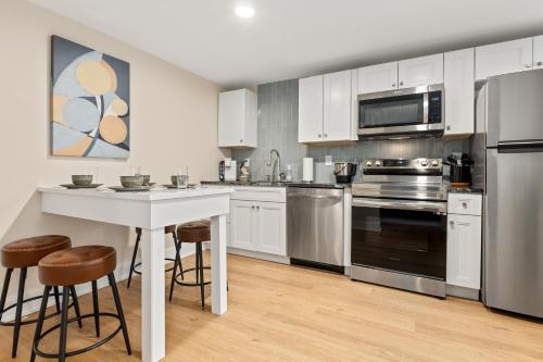 a kitchen with white cabinets and a table and stools at Surrey Beach House in Ventnor City