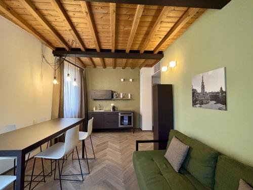 a living room with a green couch and a table at Appartamenti Saragozza a due passi da Piazza Grande - WIFI e parcheggio gratuito in Modena