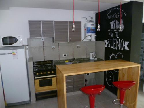 a kitchen with two red stools and a wooden counter at Departamento Corrientes in Villa María