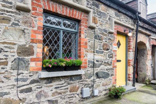 a brick building with a window with flowers in it at Duncan's Cottage at Royal Hillsborough in Hillsborough
