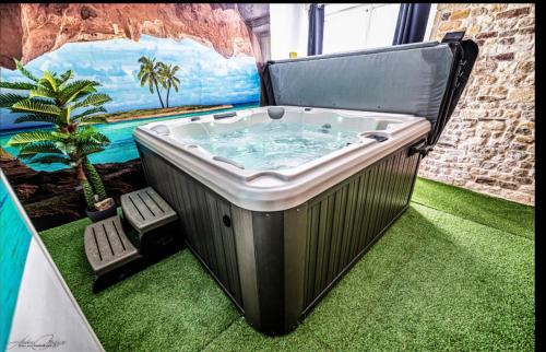 une baignoire jacuzzi dans une pièce avec une plante dans l'établissement So'Lovely maison entièrement privative avec jacuzzi à 10mn de Caen et 20mn des plages, à Vieux
