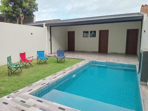 a swimming pool with chairs and a house at Hermosa Casa Vacacional con piscina privada cerca del Aeropuerto in Vila El Carmen