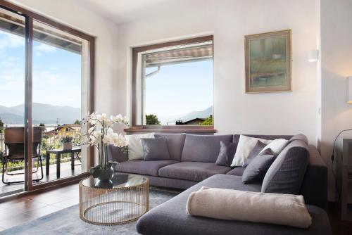 a living room with a couch and large windows at Il Bacio del sole in Maccagno Inferiore