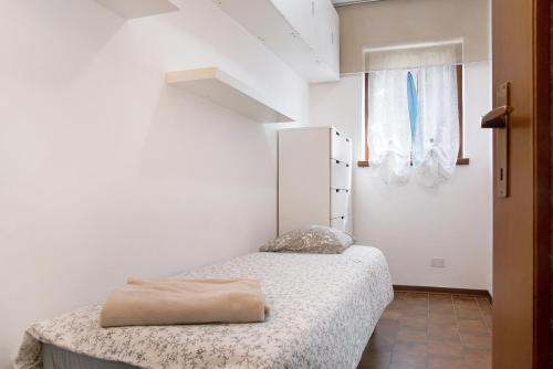 a small white bedroom with a bed and a window at Il Bacio del sole 2 in Maccagno Inferiore
