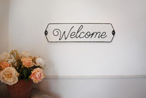 a welcome sign on a wall next to a vase of flowers at Il Bacio del sole 2 in Maccagno Inferiore