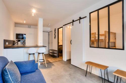 un salon avec un canapé bleu et une cuisine dans l'établissement L'Aiguille - maeva Home - 2 Pièces 4 Personnes Prestige MAE-0414, à Chamonix-Mont-Blanc