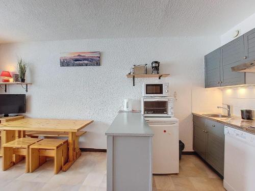 une cuisine avec une table, une table et un four micro-ondes dans l'établissement Studio proche des pistes et commerces, balcon exposé Sud, capacité 4 personnes - FR-1-275-177, à La Rosière