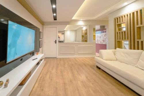 a living room with a white couch and a flat screen tv at Belíssimo Apartamento MJ44 in Maringá