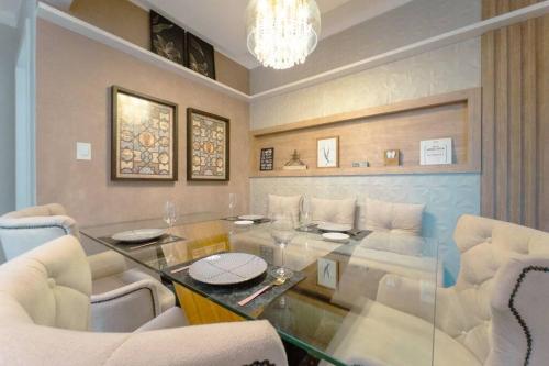 a living room with a glass table and white chairs at Belíssimo Apartamento MJ44 in Maringá