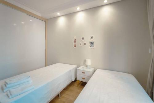 two beds in a room with white walls at Belíssimo Apartamento MJ44 in Maringá