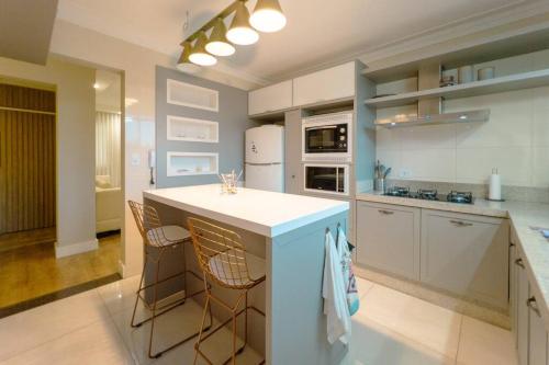a kitchen with a white counter and some chairs at Belíssimo Apartamento MJ44 in Maringá