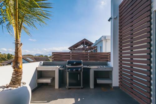 a patio with a grill and a palm tree at Luxury Penthouse with Jacuzzi, 2 min to Beach in Mont Choisy