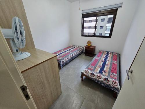a small room with two beds and a window at Duplex aconchegante na Riviera - próximo à praia in Bertioga