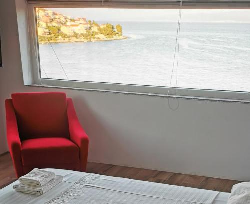 a room with a red chair and a large window at Beach House Bella Vista apartments in Trogir