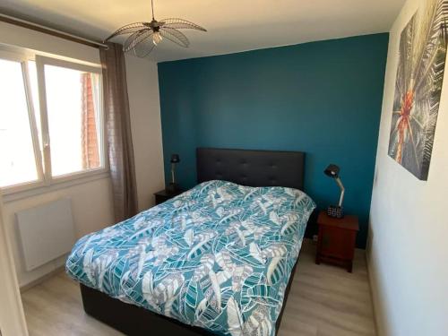 une chambre avec un lit avec un mur bleu dans l'établissement Le phare de Villers, à Villers-sur-Mer