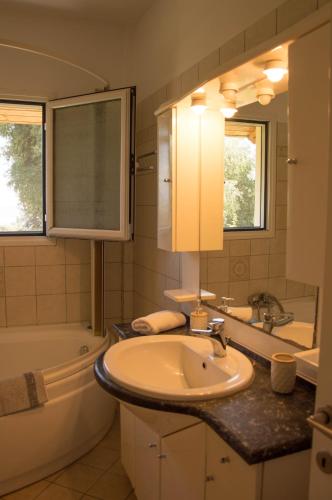 a bathroom with a sink and a tub and a mirror at Villa Marianna in Benitses